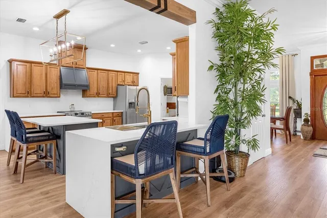 a kitchen with stainless steel appliances kitchen island granite countertop a table chairs and a refrigerator