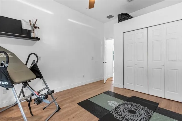 a bedroom with a bed and a lamp on table with wooden floor