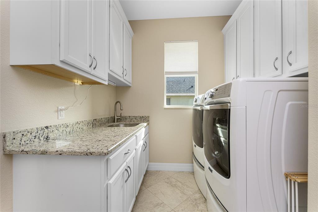199 Marker Road Rotonda West, FL 33947 - Photo 36 of 55 a utility room with stainless steel appliances granite countertop a sink a washer and dryer with wooden floor