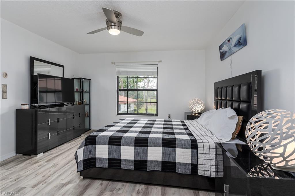 905 Augusta Boulevard, Unit 7 Naples, FL 34113 - Photo 13 of 42 a bedroom with a bed a dresser and a flat screen tv