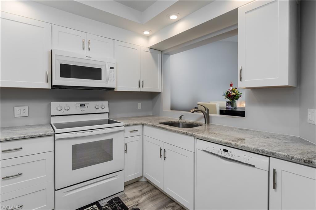905 Augusta Boulevard, Unit 7 Naples, FL 34113 - Photo 7 of 42 a kitchen with granite countertop white cabinets white stainless steel appliances and sink