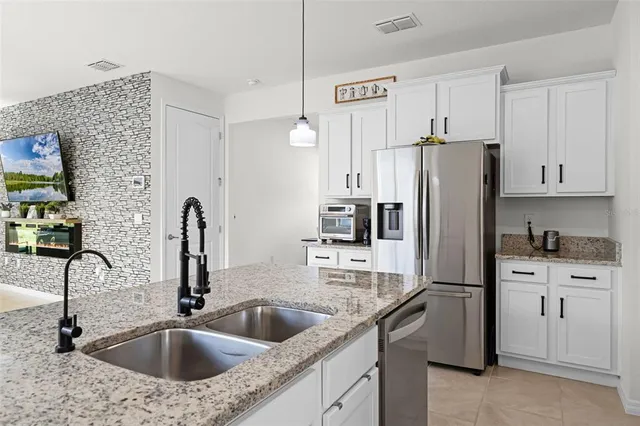 a kitchen with stainless steel appliances granite countertop a sink refrigerator and cabinets