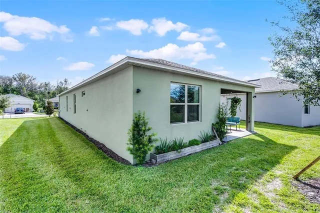 a backyard of a house with table and chairs plants and large tree