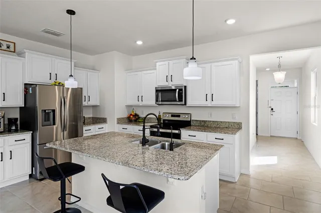 a kitchen with stainless steel appliances granite countertop a sink a stove a refrigerator a center island a stove and cabinets