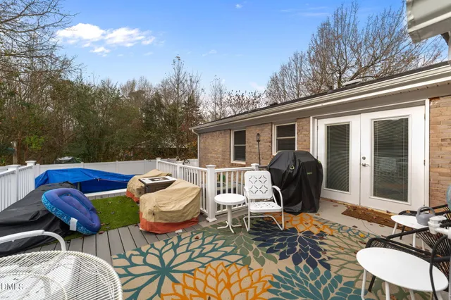 a view of a patio with table and chairs with wooden floor and fence