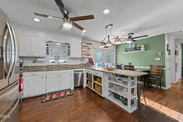 a large kitchen with a large counter top space a sink stainless steel appliances and cabinets