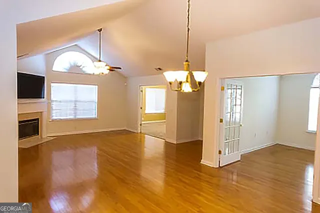 a view of a room with wooden floor fireplace and windows