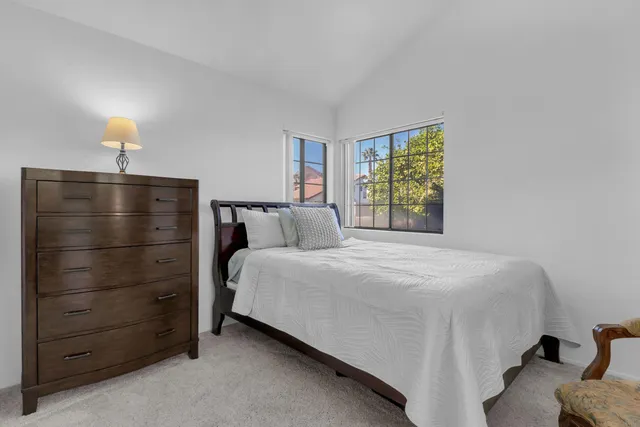 a bedroom with a bed and a lamp on dresser