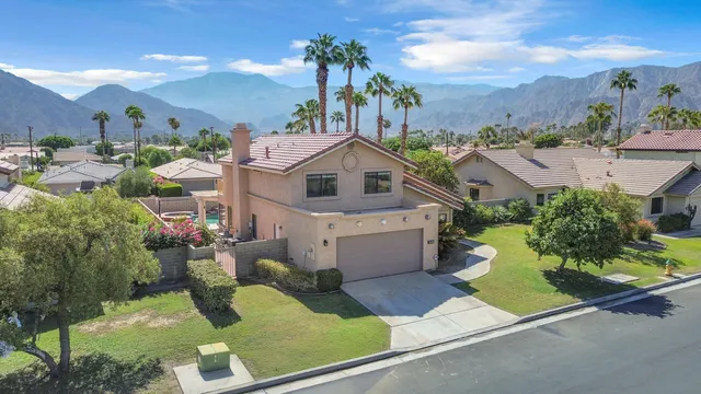 a front view of a house with a yard potted plants and large tree