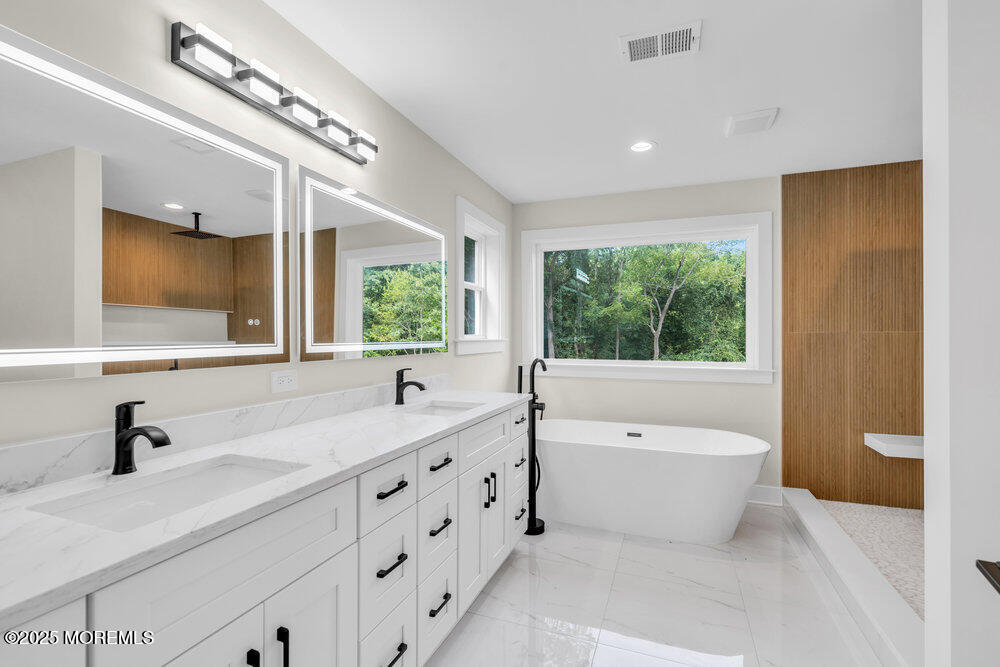 1730 Old Freehold Road Toms River, NJ 08755 - Photo 16 of 31 a bathroom with a double vanity sink a large mirror and bathtub