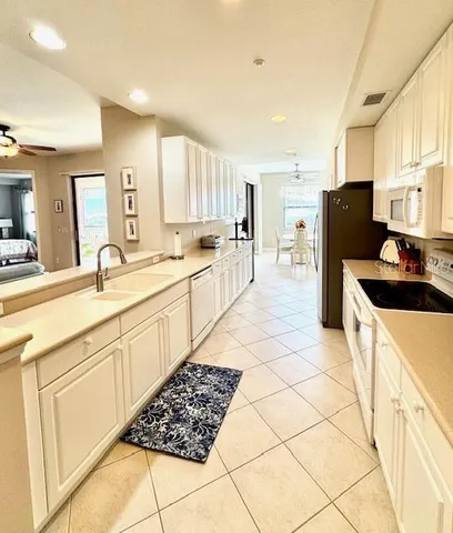 a large white kitchen with stainless steel appliances granite countertop a stove a sink a refrigerator with white cabinets and wooden floor