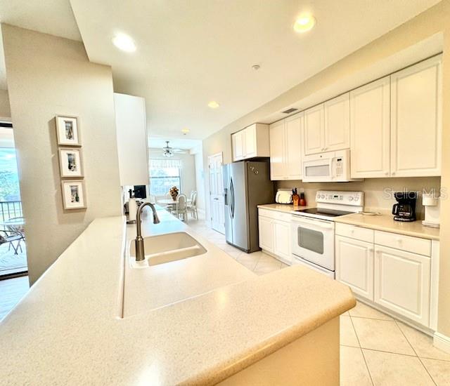 24417 Baltic Avenue, Unit 1102 Punta Gorda, FL 33955 - Photo 16 of 53 a large white kitchen with stainless steel appliances granite countertop a stove a sink a refrigerator with white cabinets and wooden floor