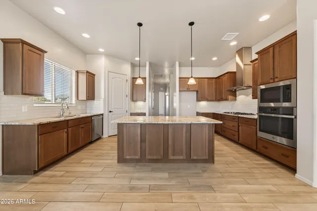 a large kitchen with stainless steel appliances kitchen island granite countertop a sink counter space and cabinets