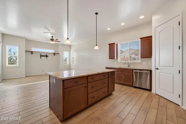 a kitchen with stainless steel appliances granite countertop a sink a stove a refrigerator and island with wooden floor