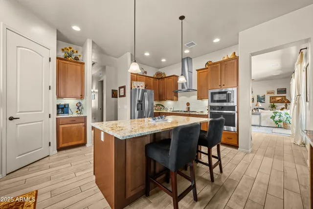a kitchen with stainless steel appliances kitchen island granite countertop a table chairs and a refrigerator