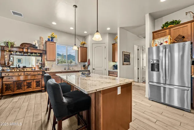 a kitchen with a table chairs refrigerator and wooden floor