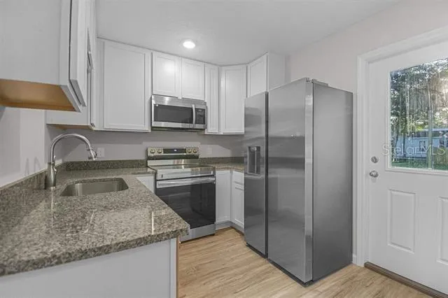 a kitchen with granite countertop a refrigerator and a sink