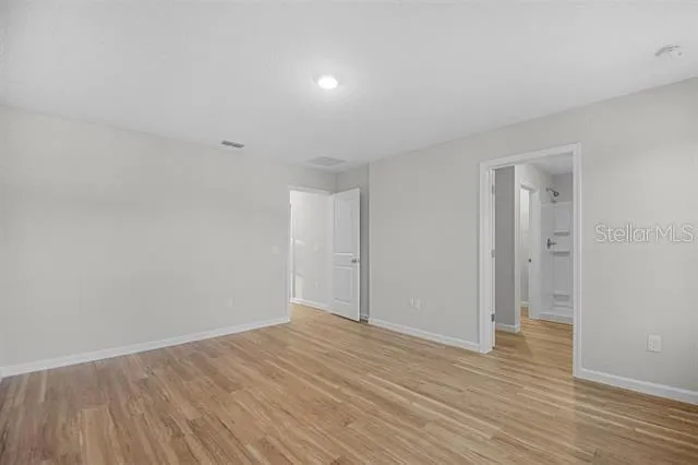 a view of an empty room with wooden floor and closet