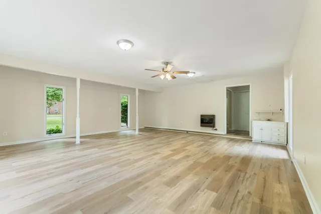 a view of an empty room with wooden floor and a window
