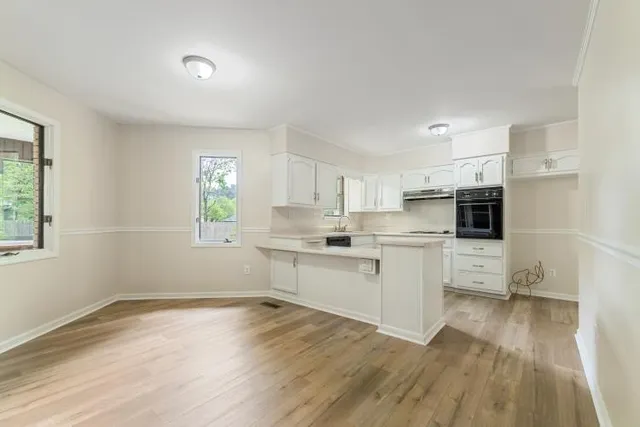 a kitchen with white cabinets and wooden floor