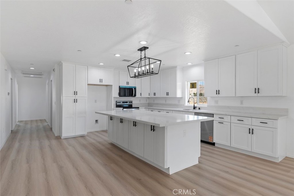 16925 Nanticoke Road Apple Valley, CA 92307 - Photo 31 of 42 a kitchen with kitchen island granite countertop a sink cabinets and wooden floor