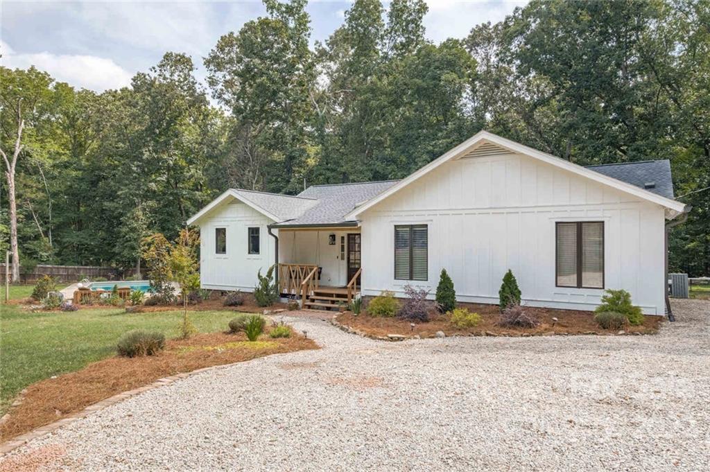 5932 Deal Road Matthews, NC 28104 - Photo 3 of 41 a view of a white house with a yard and lawn chairs under a large tree