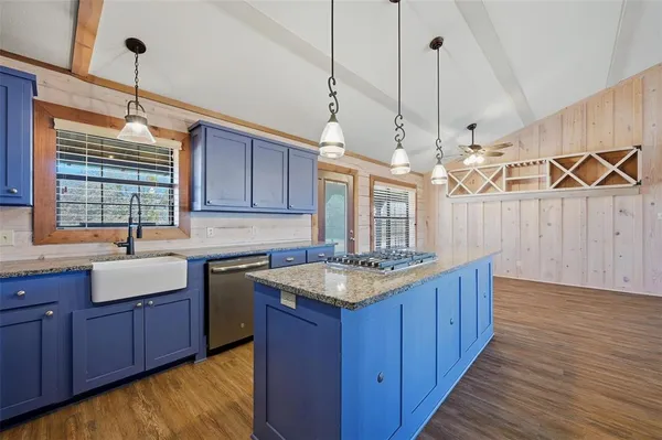 a kitchen with stainless steel appliances granite countertop a refrigerator a sink dishwasher a oven and a dining table with wooden floor