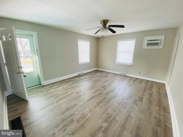 an empty room with wooden floor fan and windows