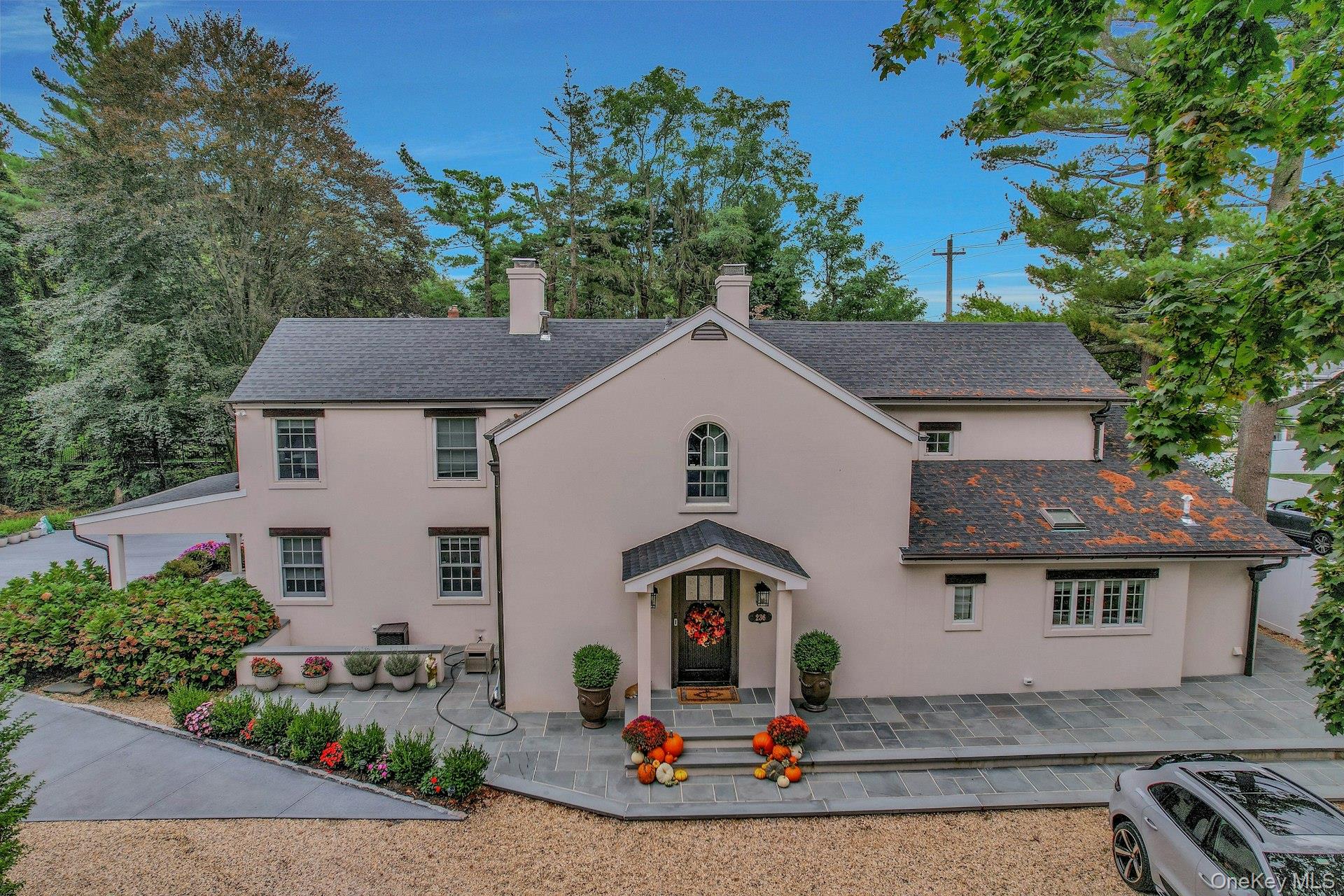 View of front of property with a chimney, stucco siding, and a high end roof