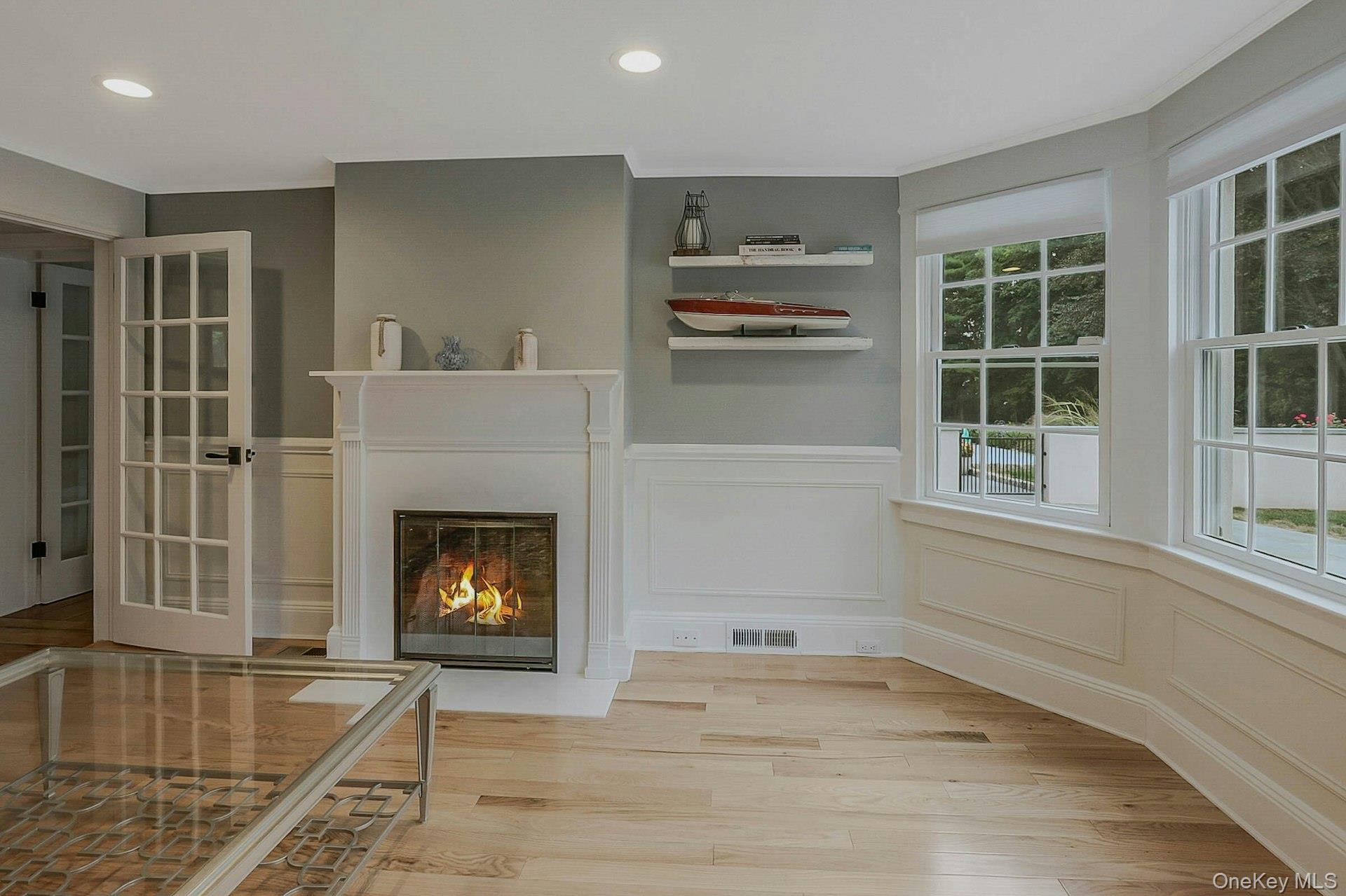236 Berry Hill Road Syosset, NY 11791 - Photo 12 of 27 Unfurnished living room featuring a decorative wall, wainscoting, a warm lit fireplace, light wood-style flooring, and recessed lighting