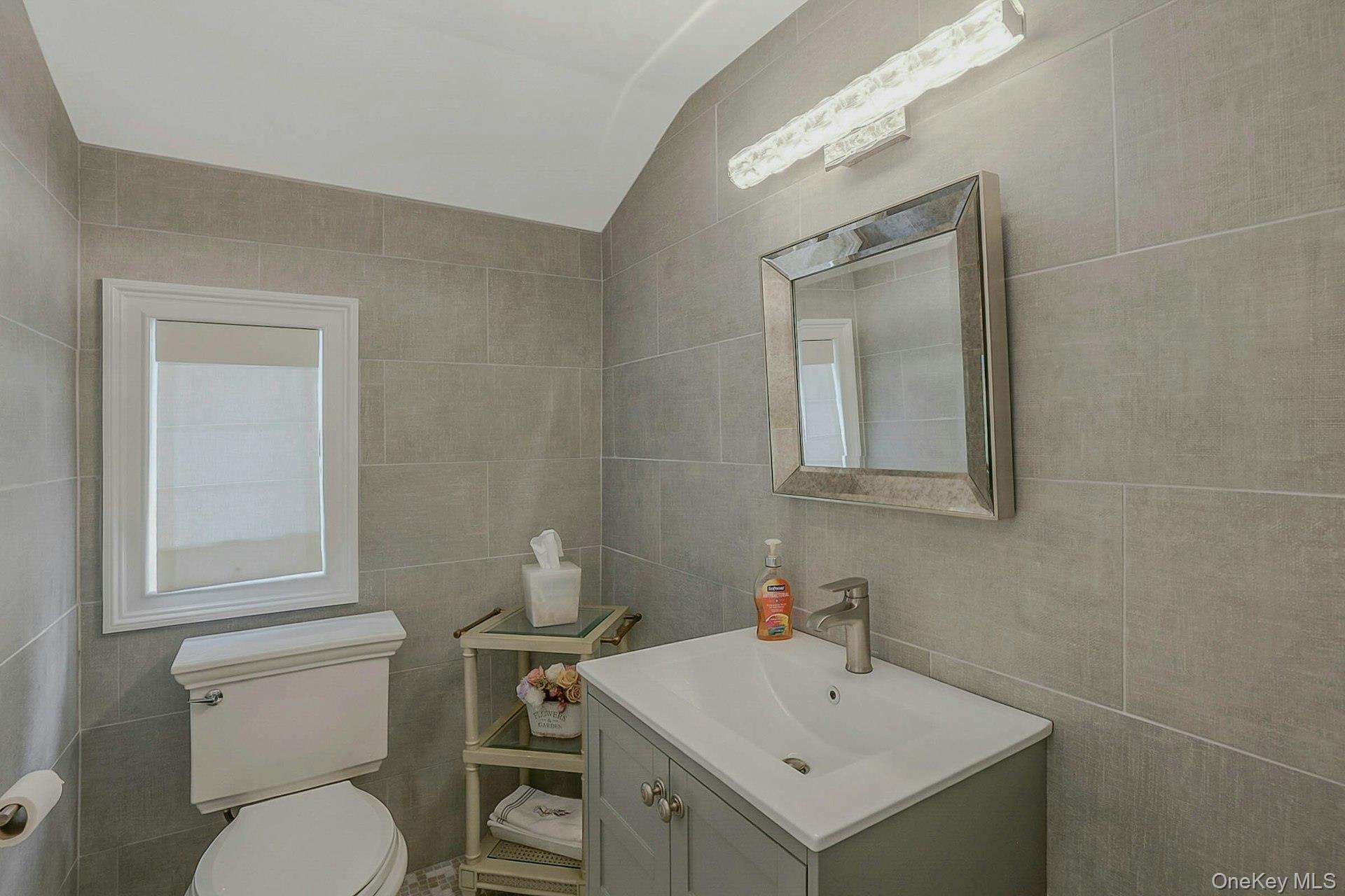 236 Berry Hill Road Syosset, NY 11791 - Photo 15 of 27 Half bathroom with tile walls, vanity, and vaulted ceiling