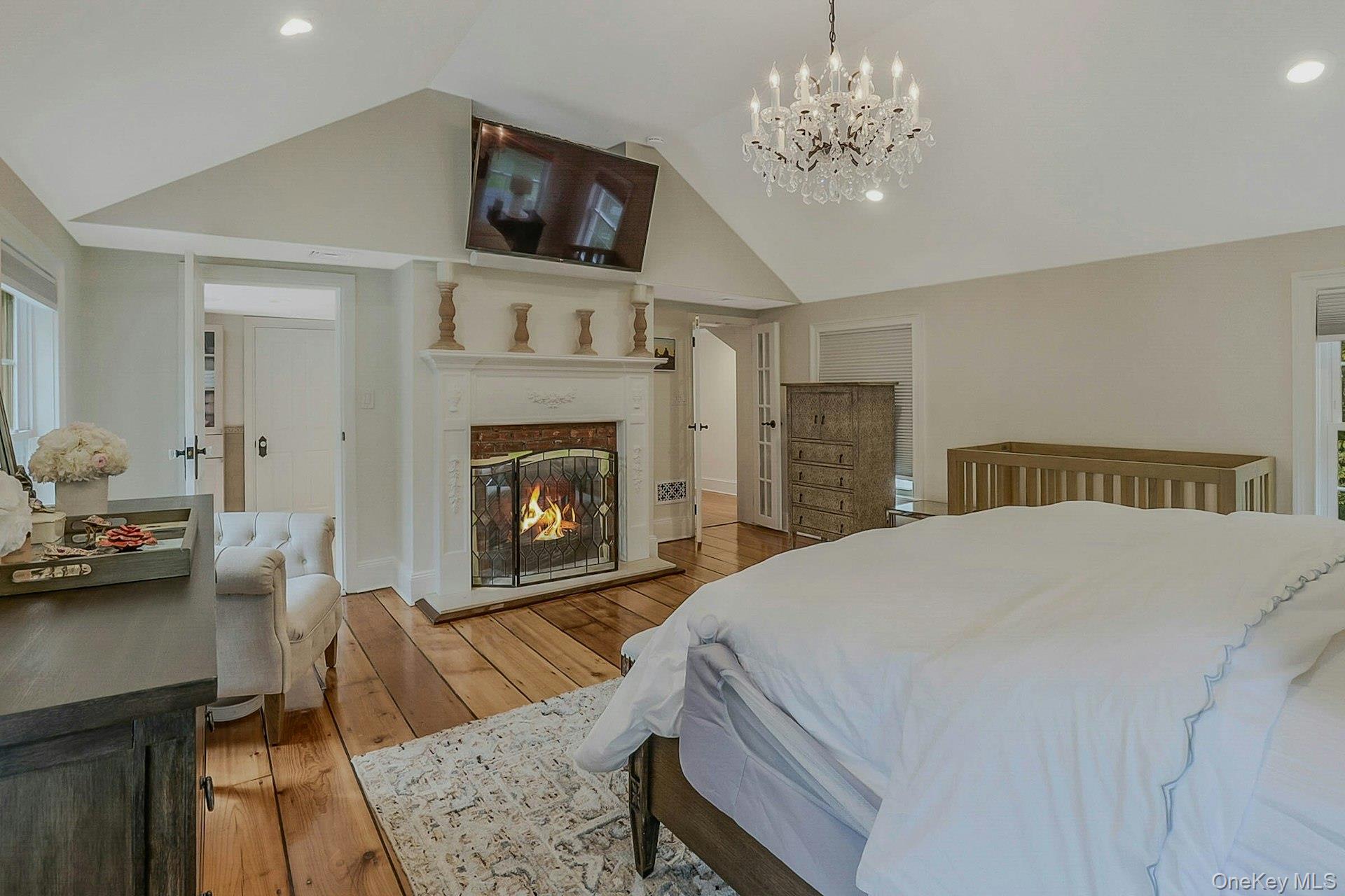 236 Berry Hill Road Syosset, NY 11791 - Photo 18 of 27 Bedroom with a glass covered fireplace, light wood-type flooring, recessed lighting, a chandelier, and high vaulted ceiling