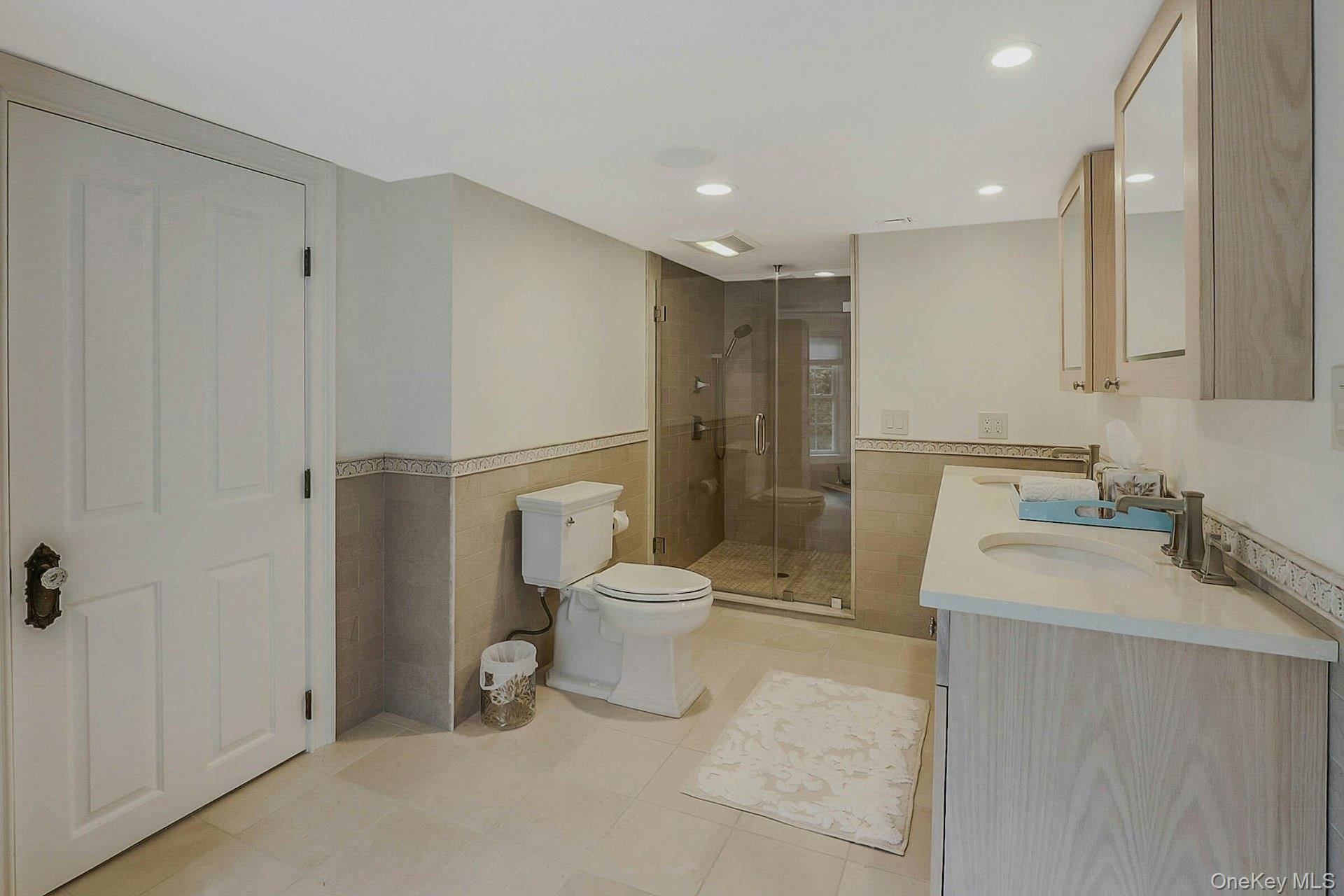 236 Berry Hill Road Syosset, NY 11791 - Photo 20 of 27 Bathroom featuring tile walls, wainscoting, a shower stall, double vanity, and light tile patterned floors