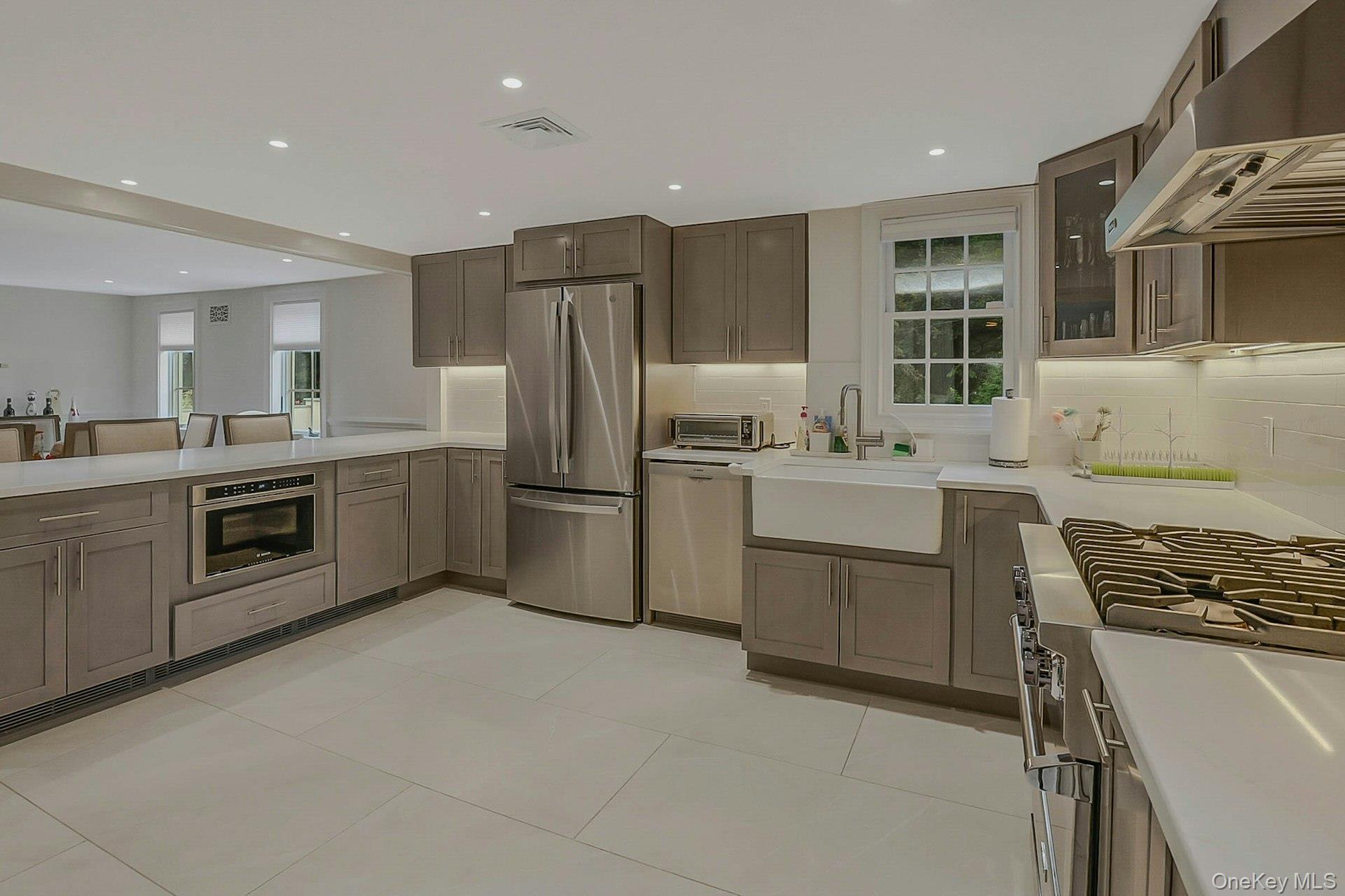 236 Berry Hill Road Syosset, NY 11791 - Photo 8 of 27 Kitchen featuring stainless steel appliances, under cabinet range hood, healthy amount of natural light, light tile patterned floors, and recessed lighting