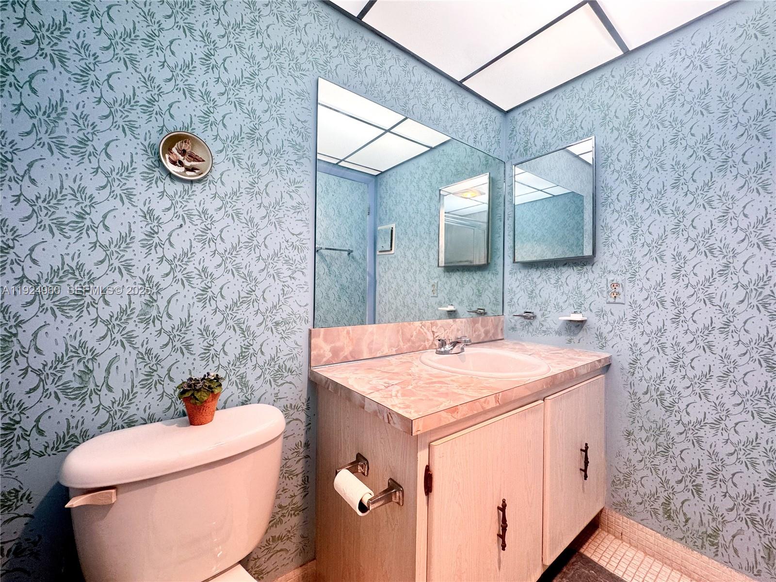 612 Normandy Lane, Unit 612 Delray Beach, FL 33484 - Photo 12 of 18 a bathroom with a toilet sink vanity and mirror