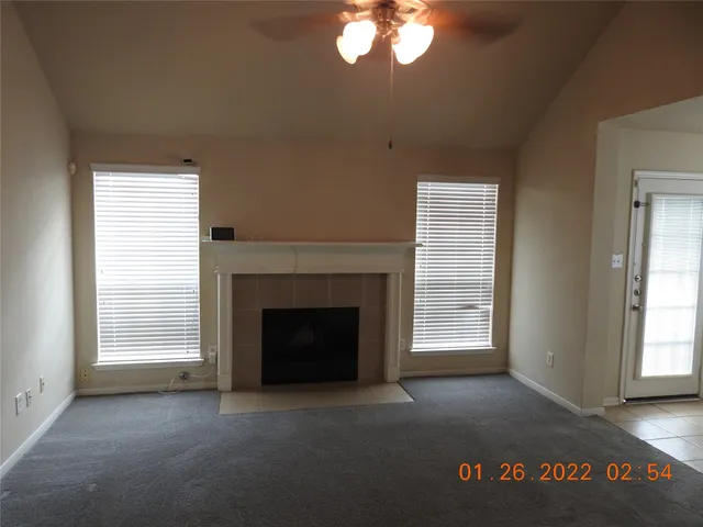 an empty room with windows fireplace and fans