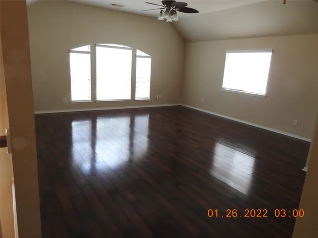 an empty room with wooden floor and windows