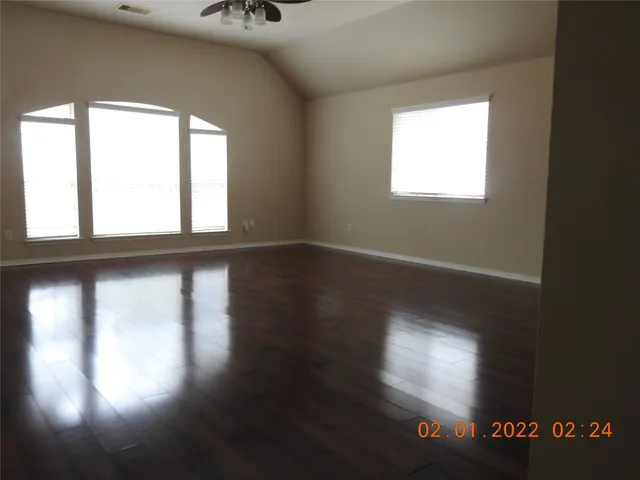 an empty room with wooden floor and windows