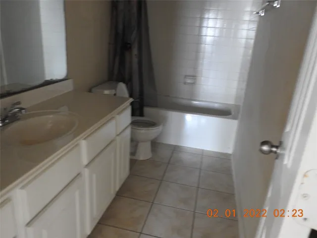 a bathroom with a granite countertop sink a toilet and tub