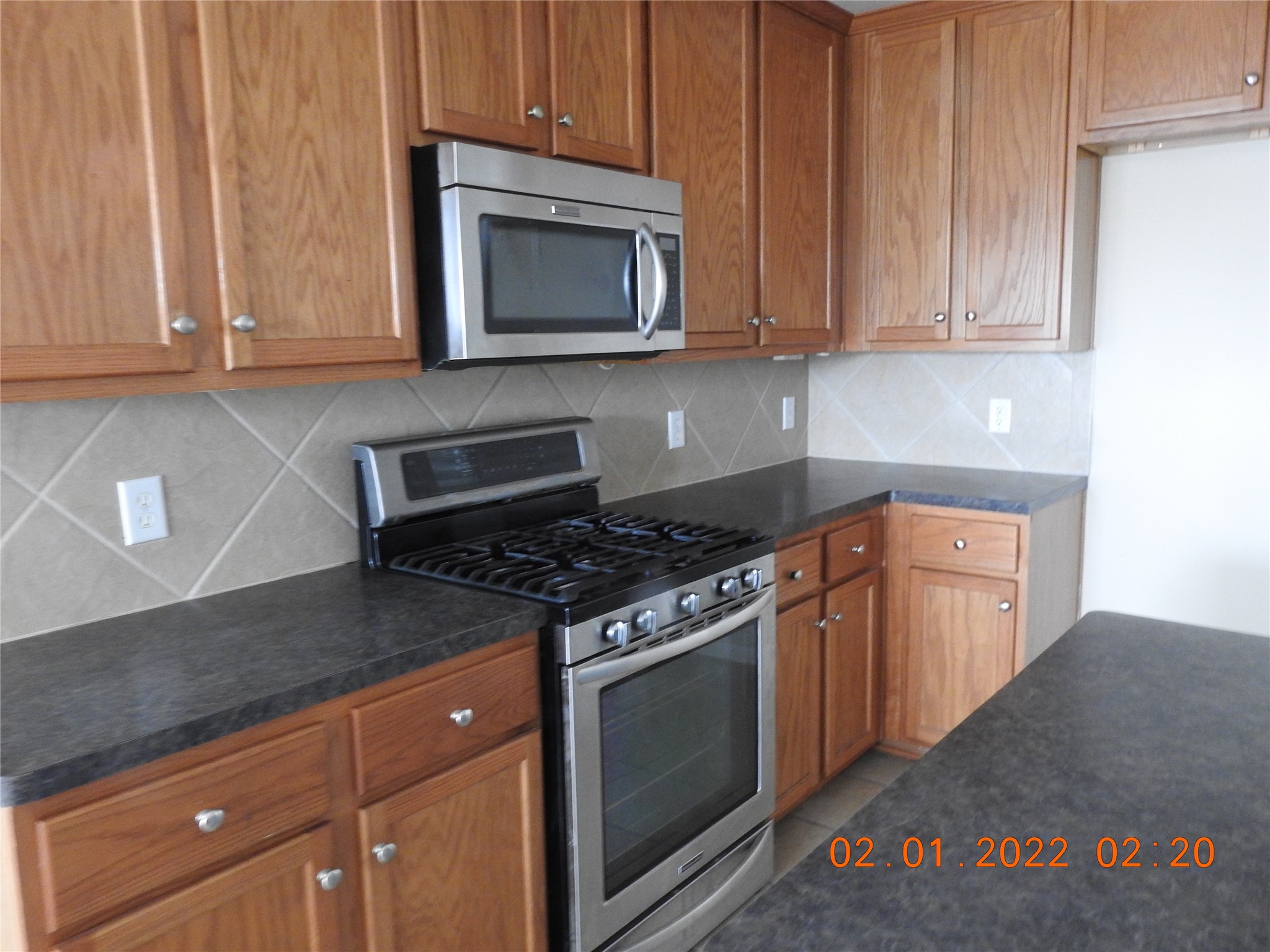 24227 Silversmith Lane Katy, TX 77493 - Photo 6 of 42 a kitchen with granite countertop a stove top oven microwave and cabinets