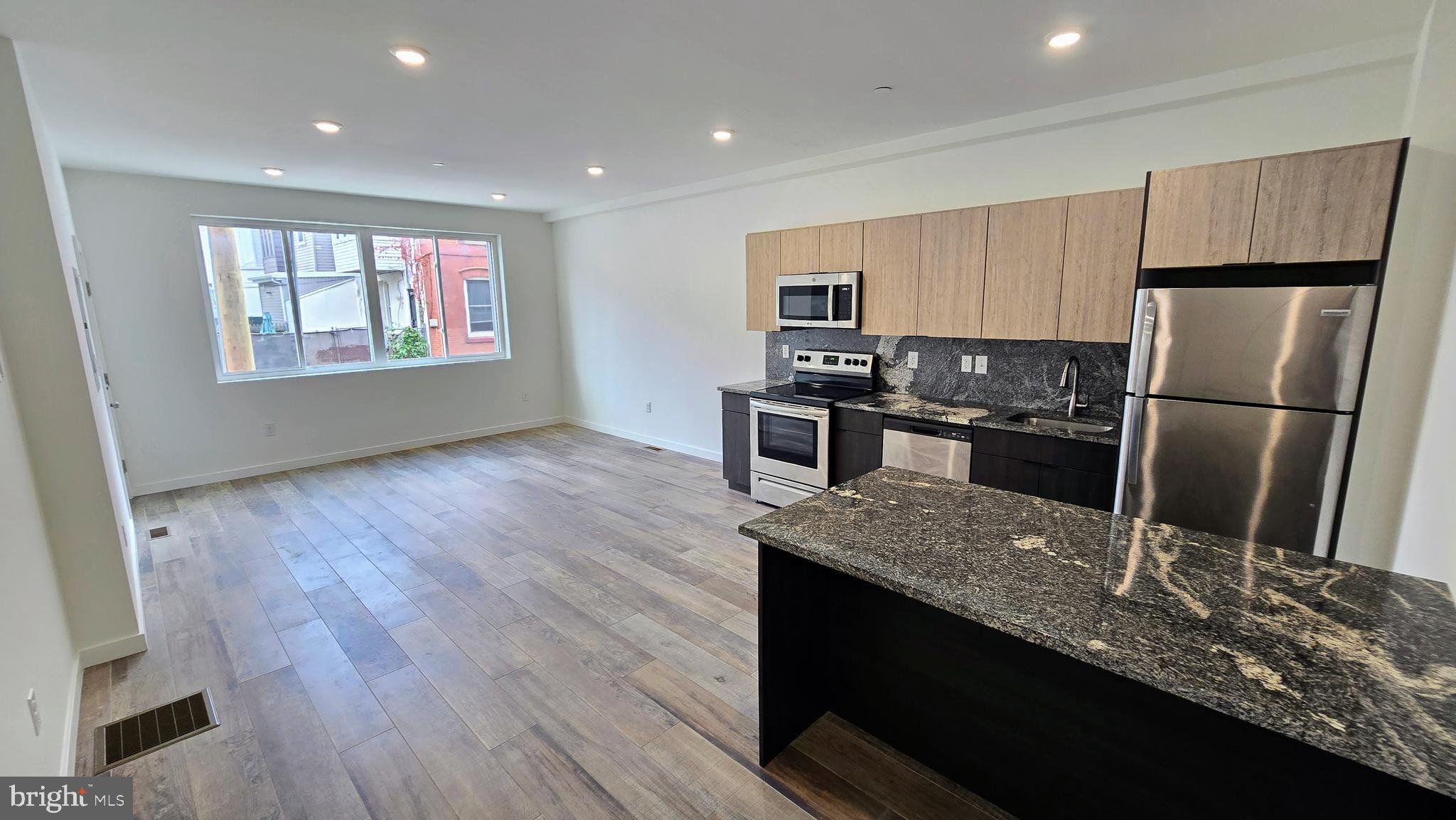 a kitchen with kitchen island granite countertop a sink appliances and wooden floor