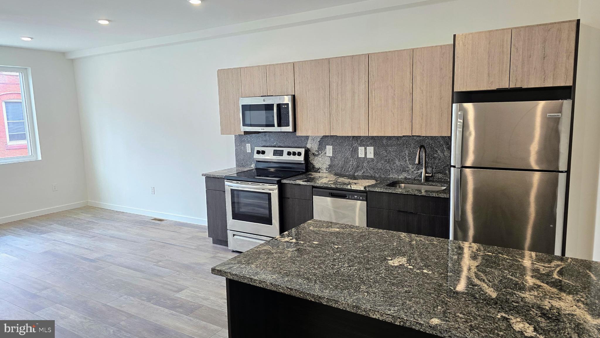 300 Budd Street, Unit C1 Philadelphia, PA 19104 - Photo 5 of 20 a kitchen with kitchen island granite countertop a refrigerator stove and oven