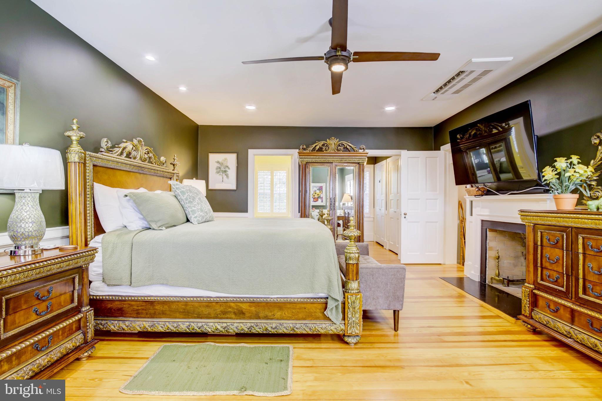 24800 Pealiquor Road Denton, MD 21629 - Photo 52 of 114 a spacious bedroom with a bed a fireplace and a flat tv screen on dresser