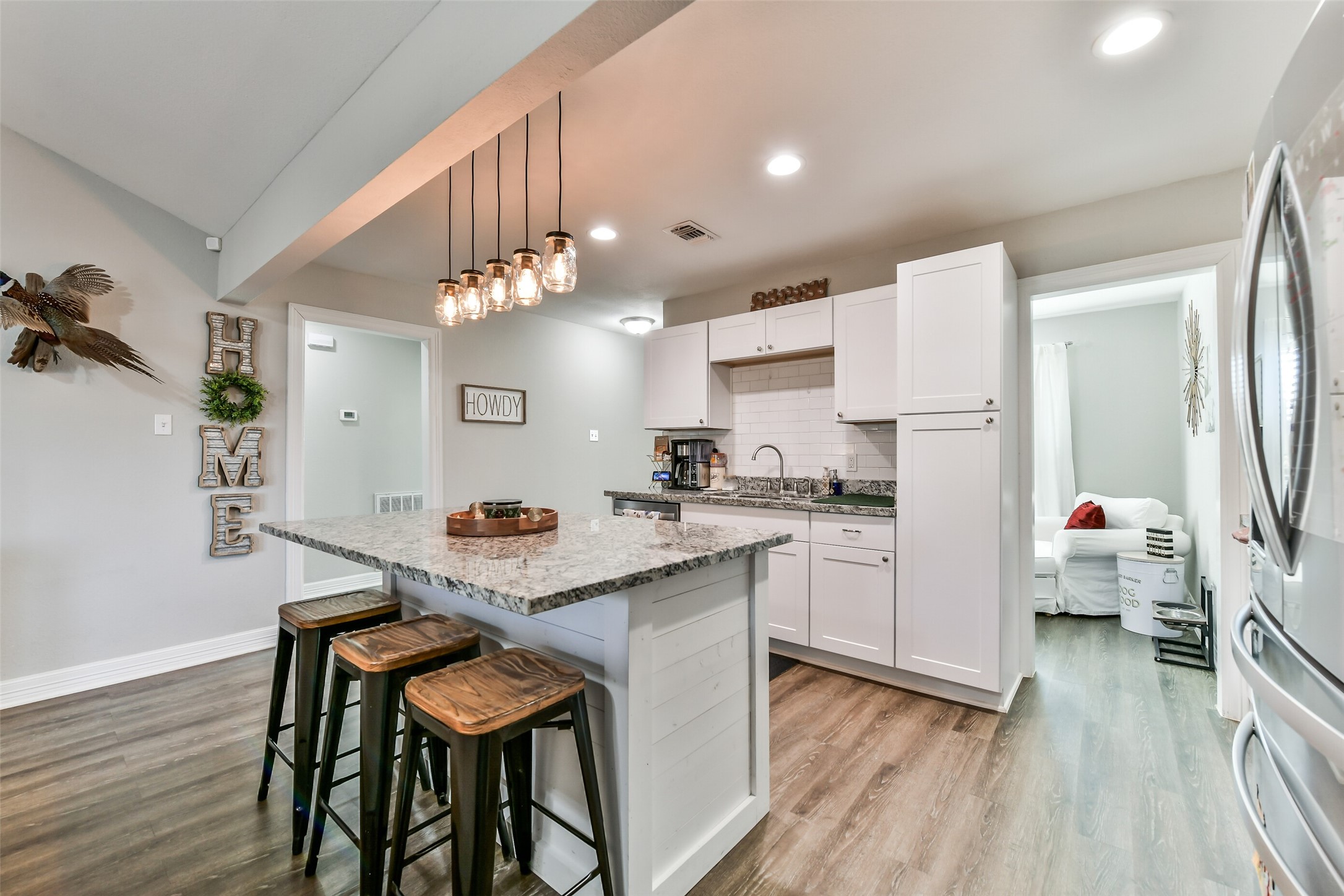 5421 Bramble Lane Dickinson, TX 77539 - Photo 7 of 26 a kitchen with stainless steel appliances kitchen island granite countertop a refrigerator a stove a sink dishwasher and white cabinets with wooden floor