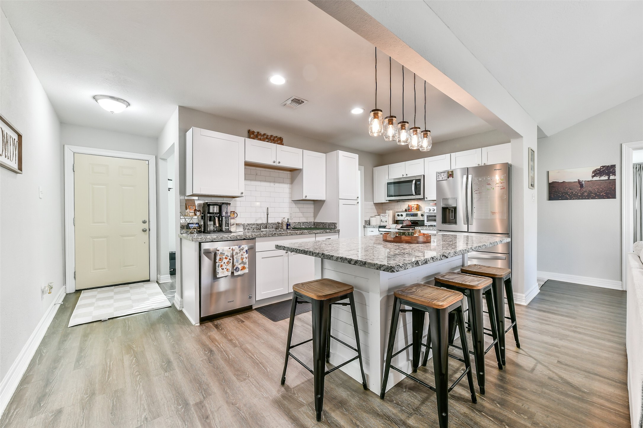5421 Bramble Lane Dickinson, TX 77539 - Photo 9 of 26 a kitchen with kitchen island granite countertop wooden floors and stainless steel appliances