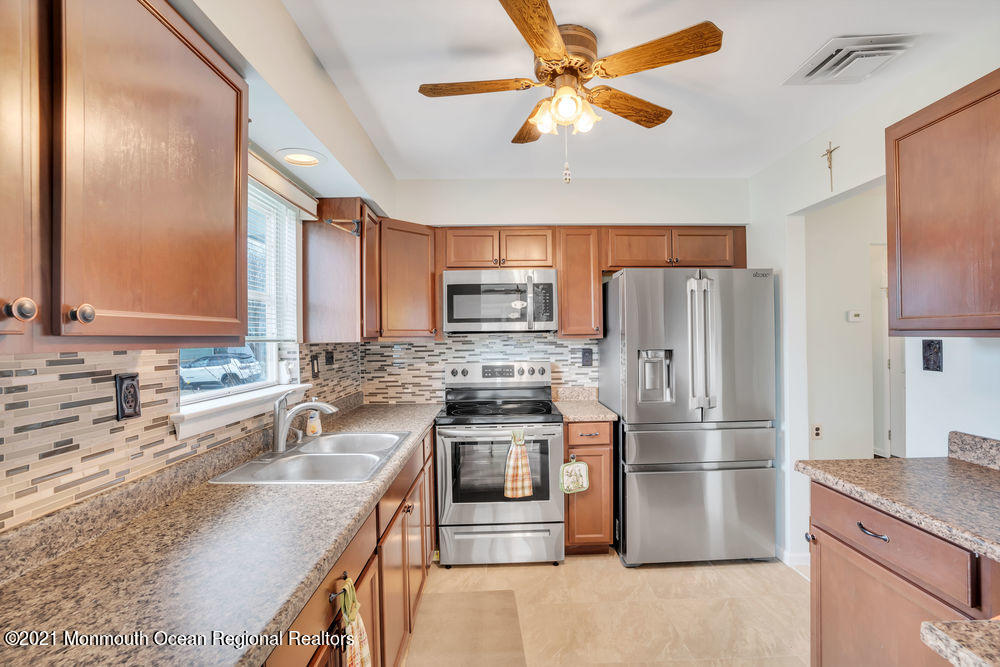 54 Markham Road Brick, NJ 08724 - Photo 18 of 35 a kitchen with stainless steel appliances granite countertop a sink a stove a refrigerator a washer dryer and white cabinets