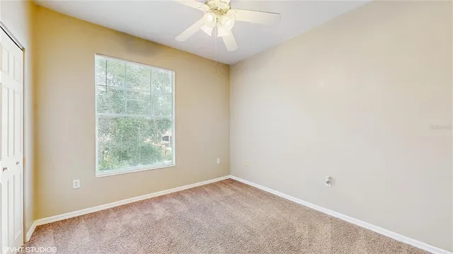 an empty room with a window and a fan