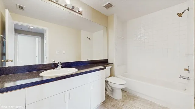 a bathroom with a granite countertop sink a toilet and a bathtub