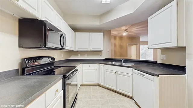 a kitchen with granite countertop a sink a stove and cabinets