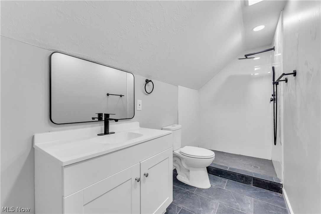 5581 Dunham Road Maple Heights, OH 44137 - Photo 27 of 33 Bathroom with vaulted ceiling, oversized vanity, toilet, tile floors, and walk in shower